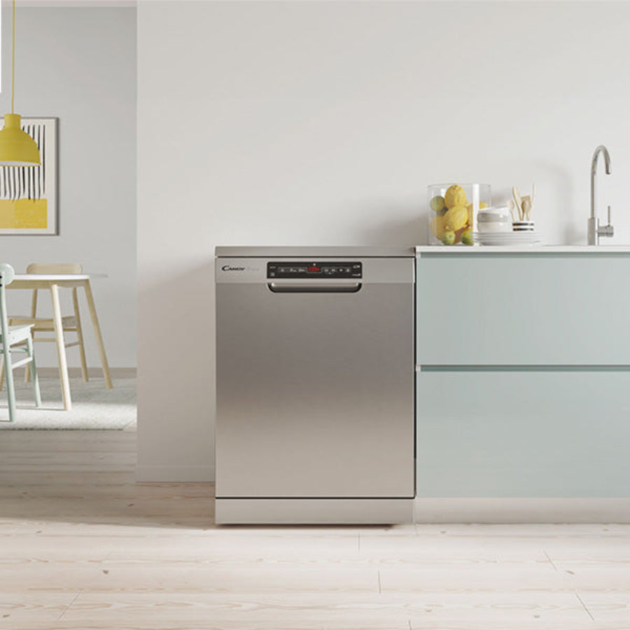 Particolare di una cucina moderna con lavastoviglie in acciaio inox, piano di lavoro chiaro con stoviglie e parete bianca, decorata con lampada gialla e quadro.